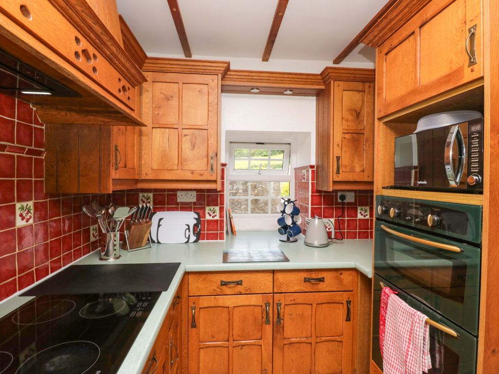 A kitchen with wood cabinets and appliances at Burnbank Cottage in Grange-Over-Sands