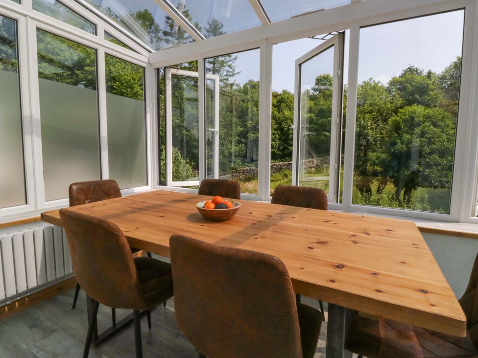 A conservatory with a wooden table and chairs at Burnbank Cottage in Grange-Over-Sands