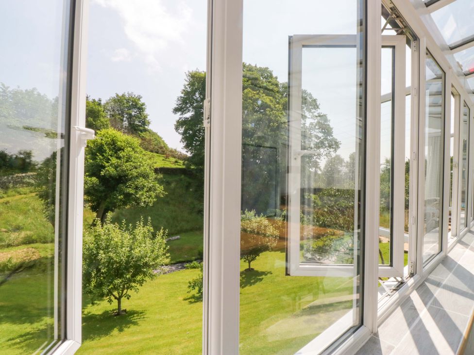 A conservatory with windows overlooking a garden at Burnbank Cottage in Grange-Over-Sands