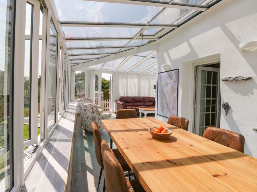 A conservatory with a wooden table and chairs at Burnbank Cottage in Grange-Over-Sands