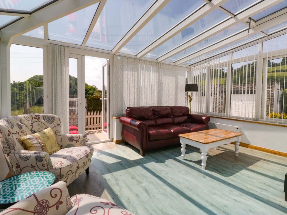 A conservatory with sofas and a table at Burnbank Cottage in Grange-Over-Sands