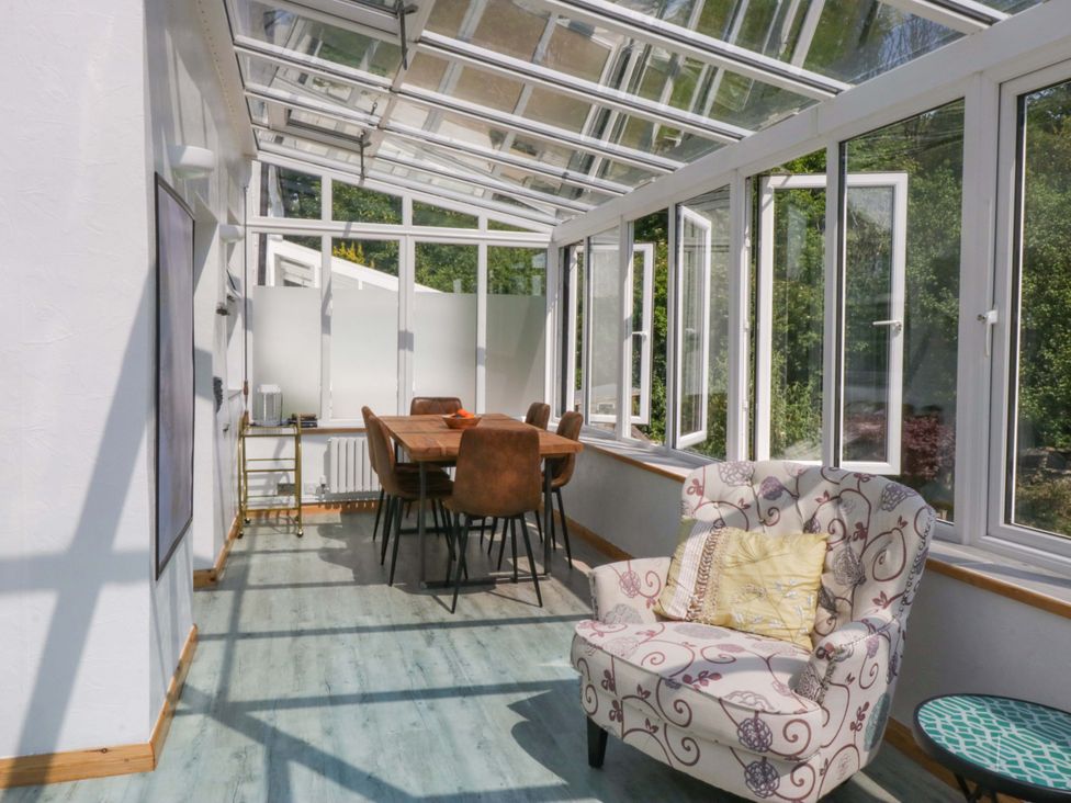 A conservatory with a table and chairs at Burnbank Cottage in Grange-Over-Sands