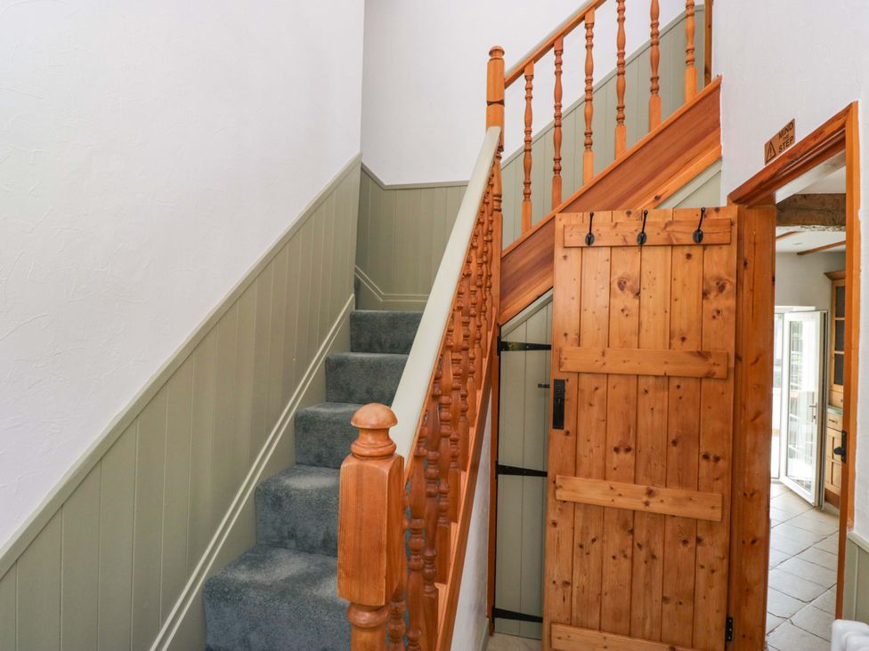 A staircase and wooden door in a hallway at Burnbank Cottage in Grange-Over-Sands