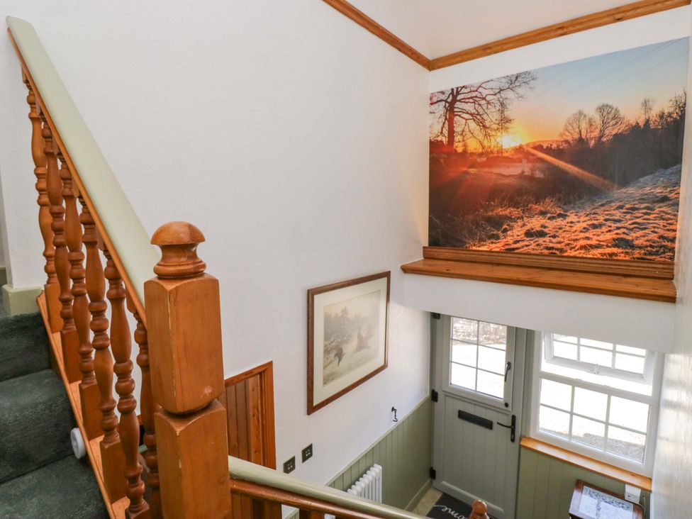 A staircase with a wall photograph and door at Burnbank Cottage in Grange-Over-Sands