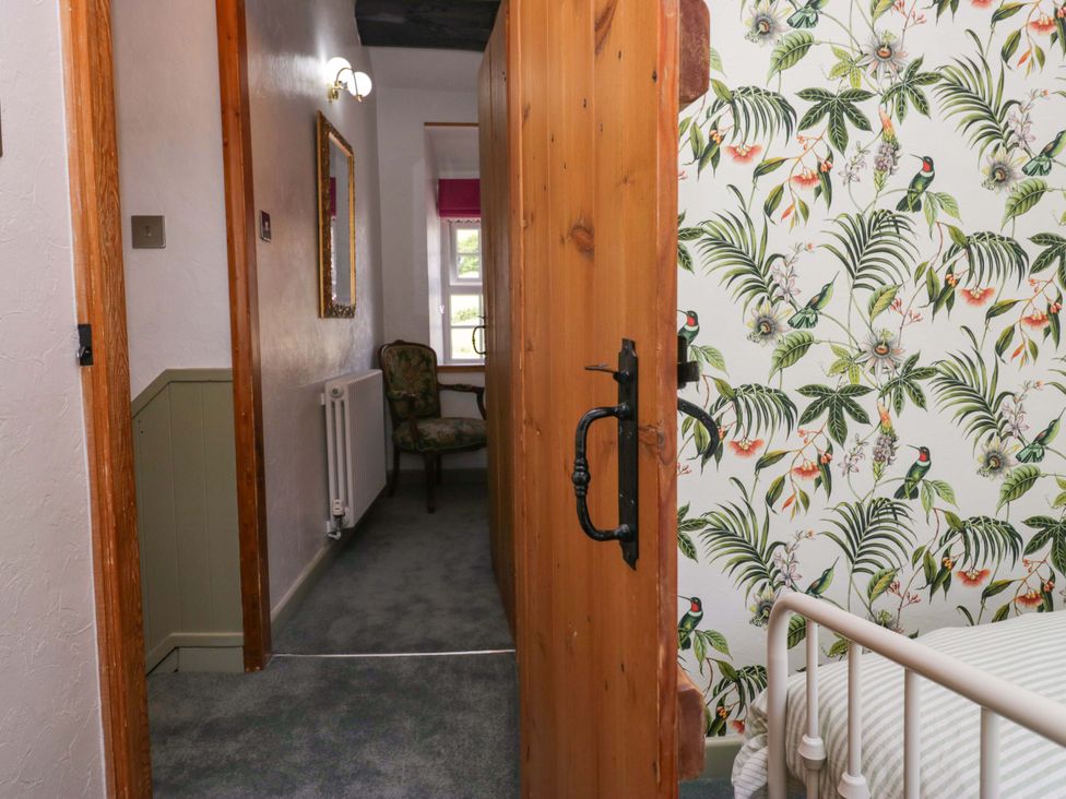 A hallway with a door and a chair at Burnbank Cottage in Grange-Over-Sands