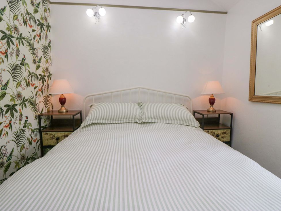 A bedroom with a bed and nightstands at Burnbank Cottage Grange-Over-Sands