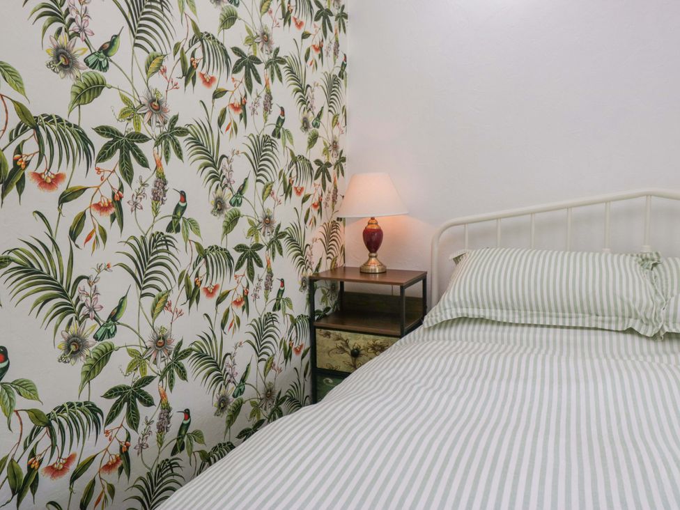 A bedroom with a bed and lamp at Burnbank Cottage in Grange-Over-Sands
