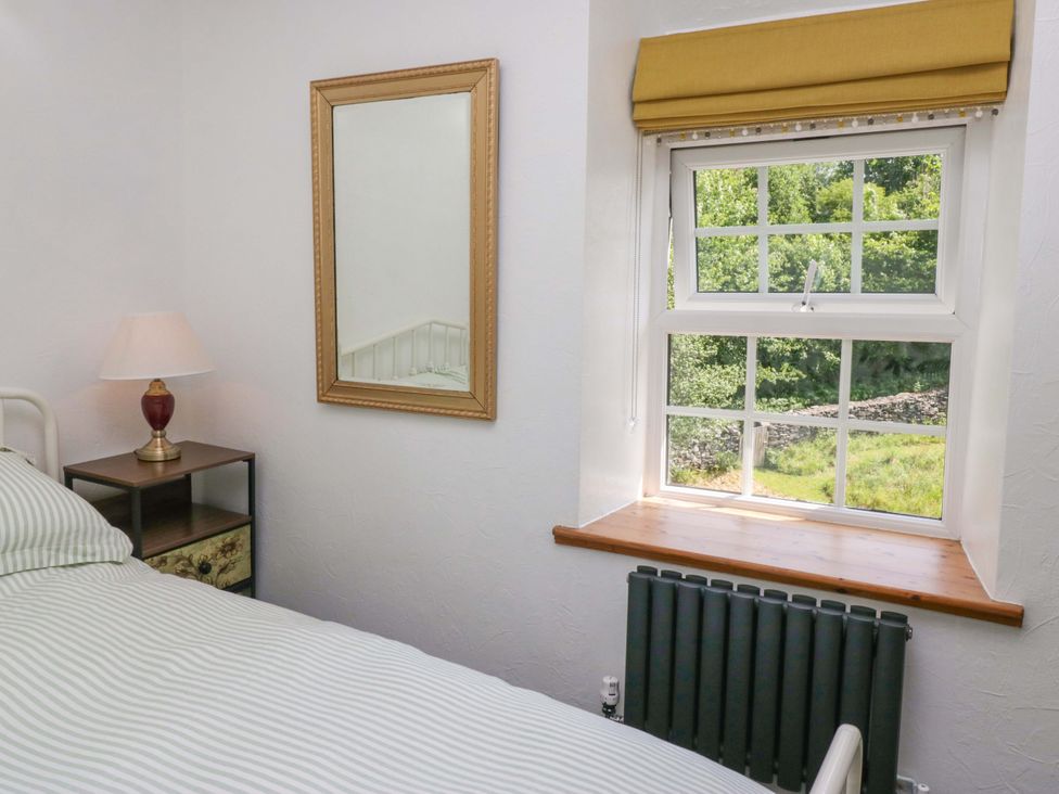 A bedroom with a bed and lamp at Burnbank Cottage in Grange-Over-Sands