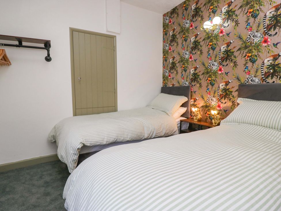 A bedroom with two beds and a patterned wall at Burnbank Cottage in Grange-Over-Sands