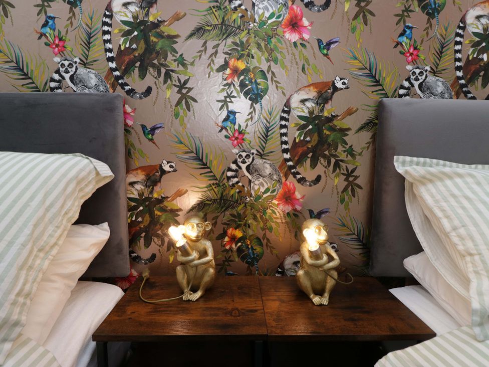 A bedroom with a bed and decorative wallpaper at Burnbank Cottage in Grange-Over-Sands