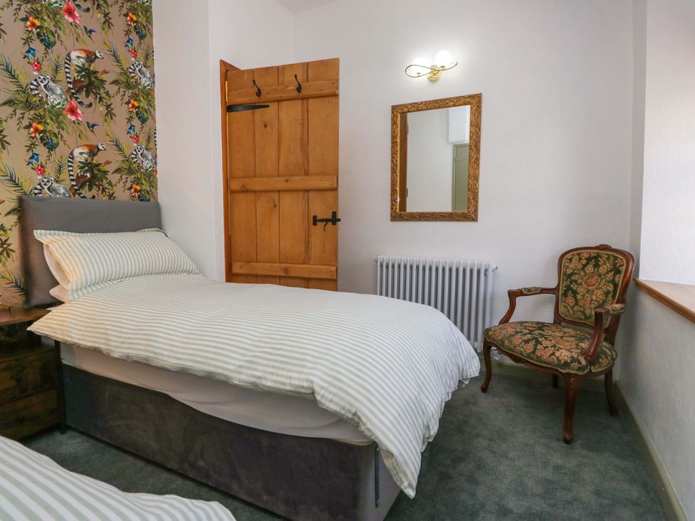 A bedroom with a bed and armchair at Burnbank Cottage in Grange-Over-Sands