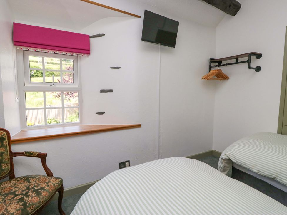 A bedroom with a bed, television, and window at Burnbank Cottage in Grange-Over-Sands