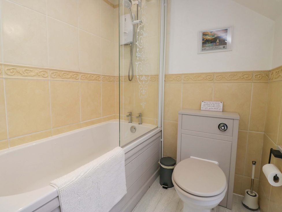 A bathroom with a bathtub and shower unit at Burnbank Cottage in Grange-Over-Sands