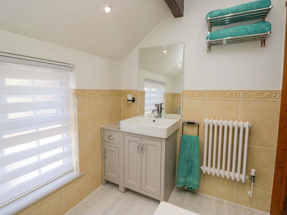 A bathroom with a sink and mirror at Burnbank Cottage in Grange-Over-Sands