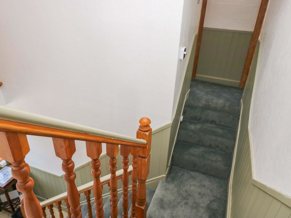 A staircase with a carpet and wooden handrail at Burnbank Cottage in Grange-Over-Sands