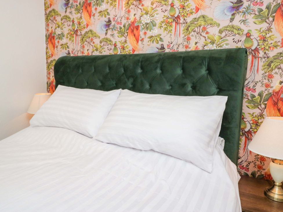 A bed with pillows and a green headboard in a bedroom at Burnbank Cottage in Grange-Over-Sands
