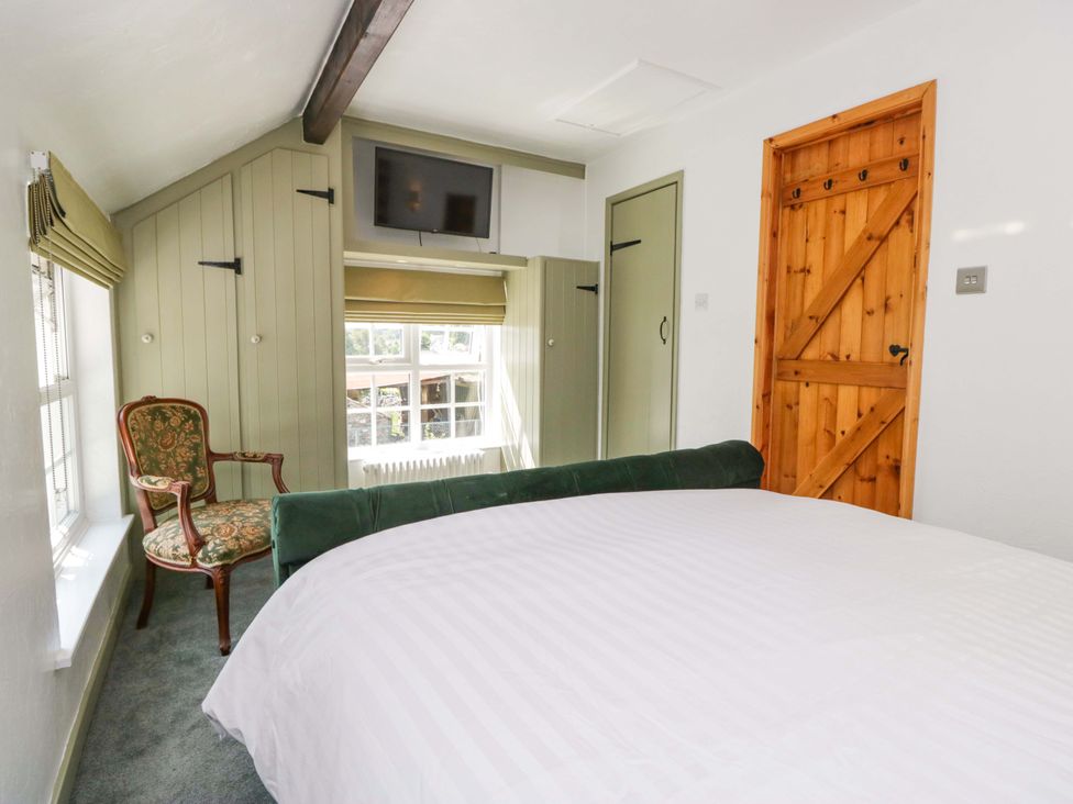 A bedroom with a bed and a chair at Burnbank Cottage Grange-Over-Sands
