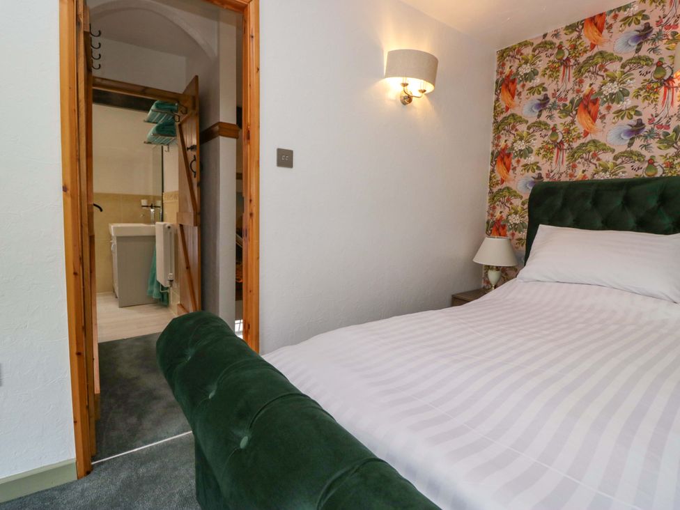 A bedroom with a bed and a door leading to a bathroom at Burnbank Cottage in Grange-Over-Sands