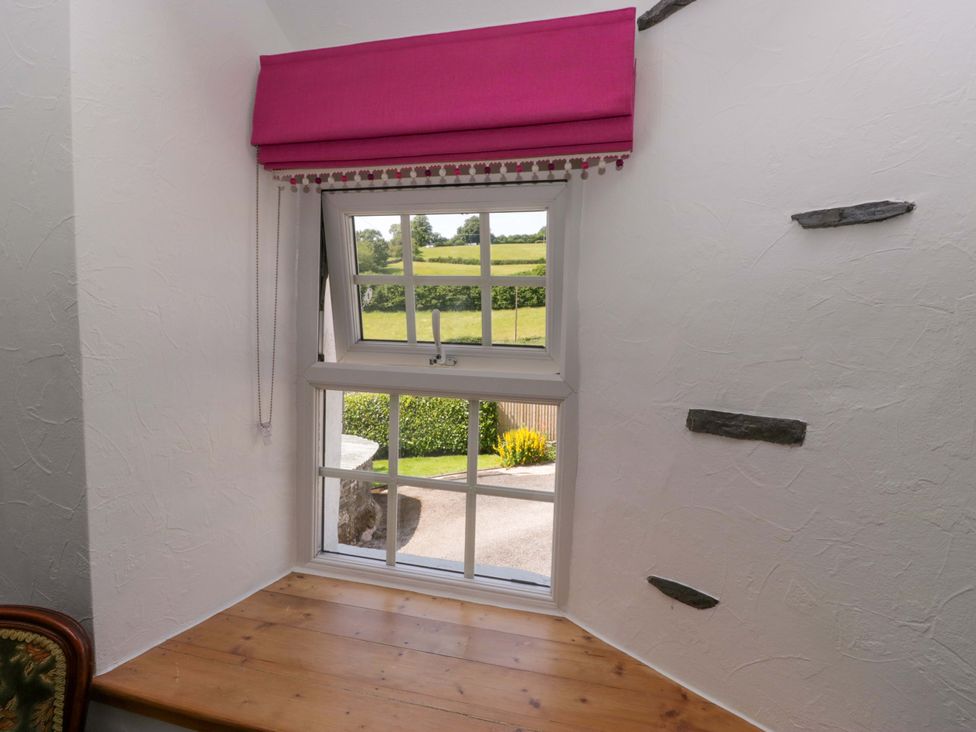 A window with a wooden sill and pink treatment at Burnbank Cottage in Grange-Over-Sands