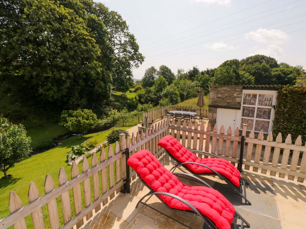 An outdoor area with red deck chairs and a table at Burnbank Cottage in Grange-Over-Sands