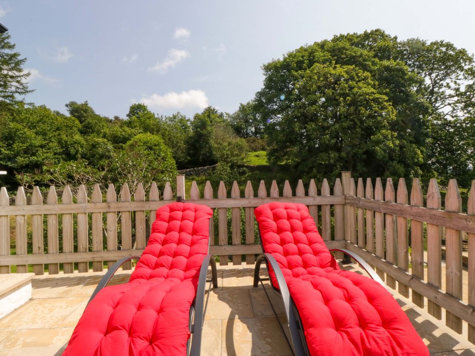 Two red deck chairs on a patio at Burnbank Cottage in Grange-Over-Sands