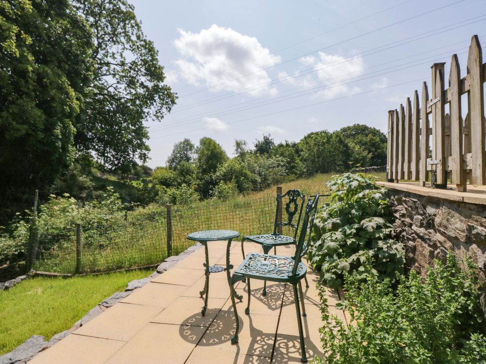 A table and chairs on a patio in the garden at Burnbank Cottage in Grange-Over-Sands