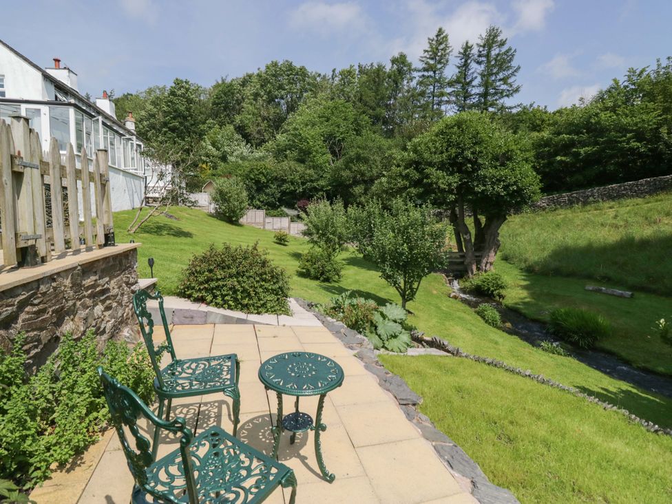 A garden with green chairs and a table at Burnbank Cottage in Grange-Over-Sands