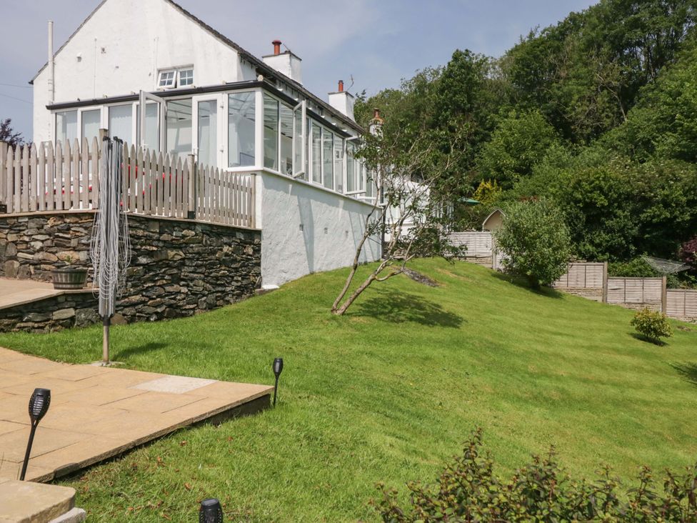 A garden with a conservatory and steps at Burnbank Cottage Grange-Over-Sands