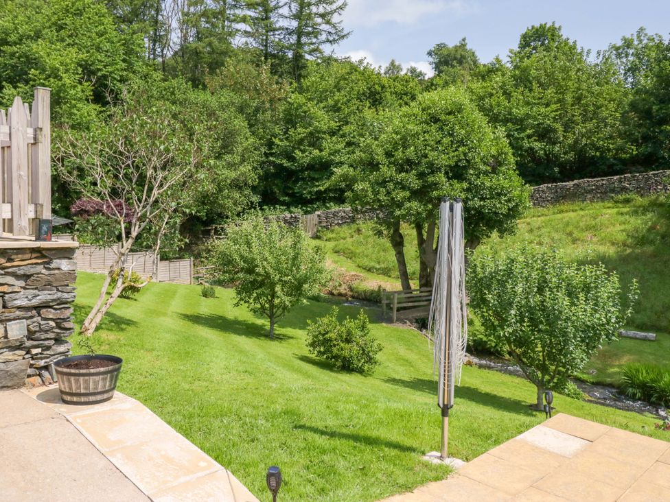 A garden with trees and a bench at Burnbank Cottage in Grange-Over-Sands