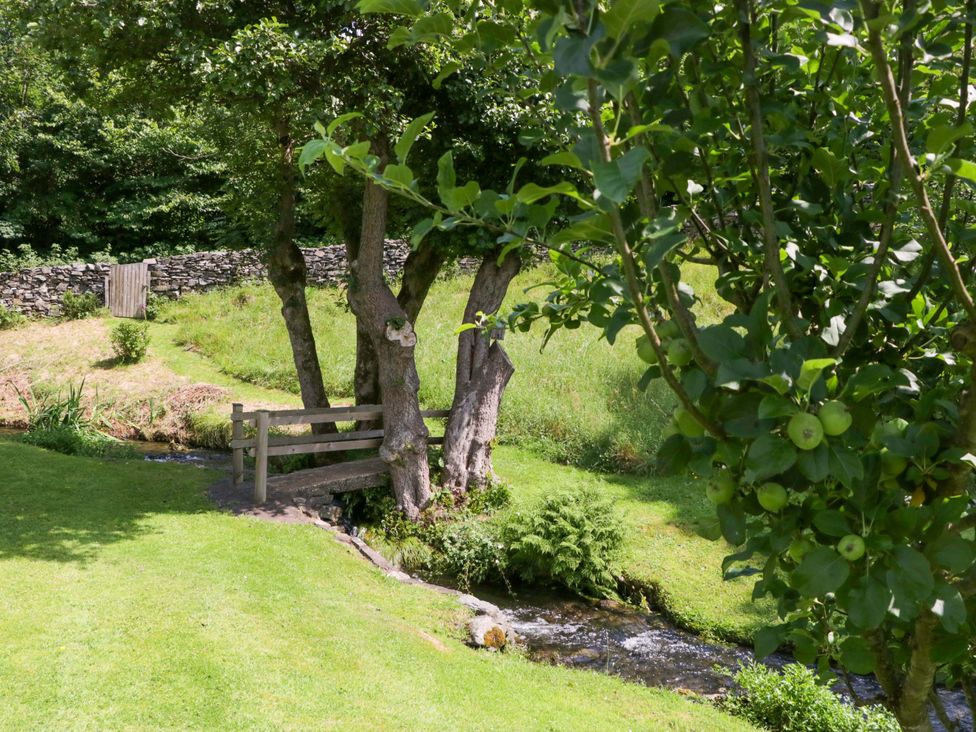 A stream and a wooden fence by trees at Burnbank Cottage Grange-Over-Sands