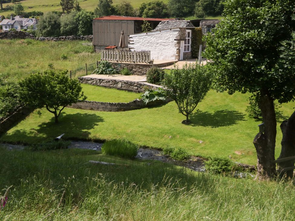 A garden with trees and a stream at Burnbank Cottage in Grange-Over-Sands