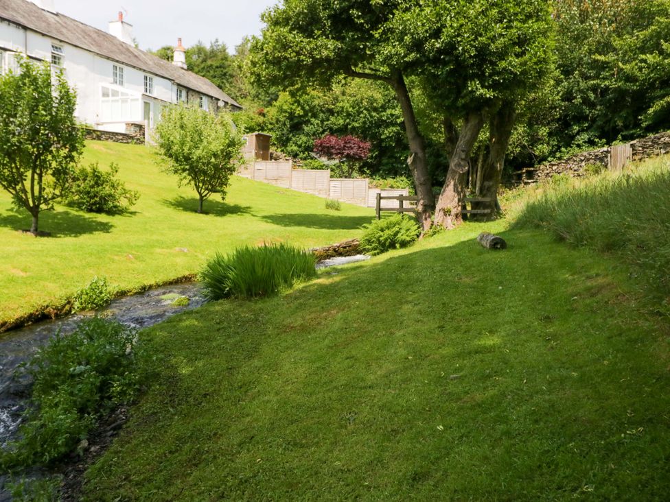 A garden with a stream and trees at Burnbank Cottage in Grange-Over-Sands
