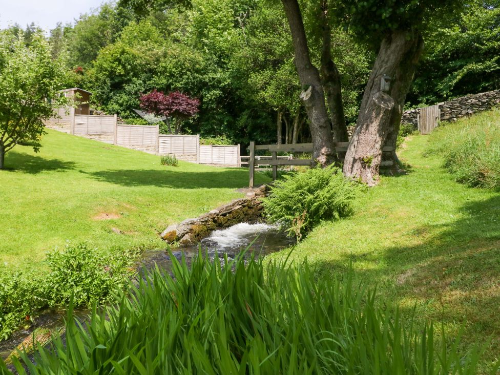 A garden with a stream and trees at Burnbank Cottage in Grange-Over-Sands