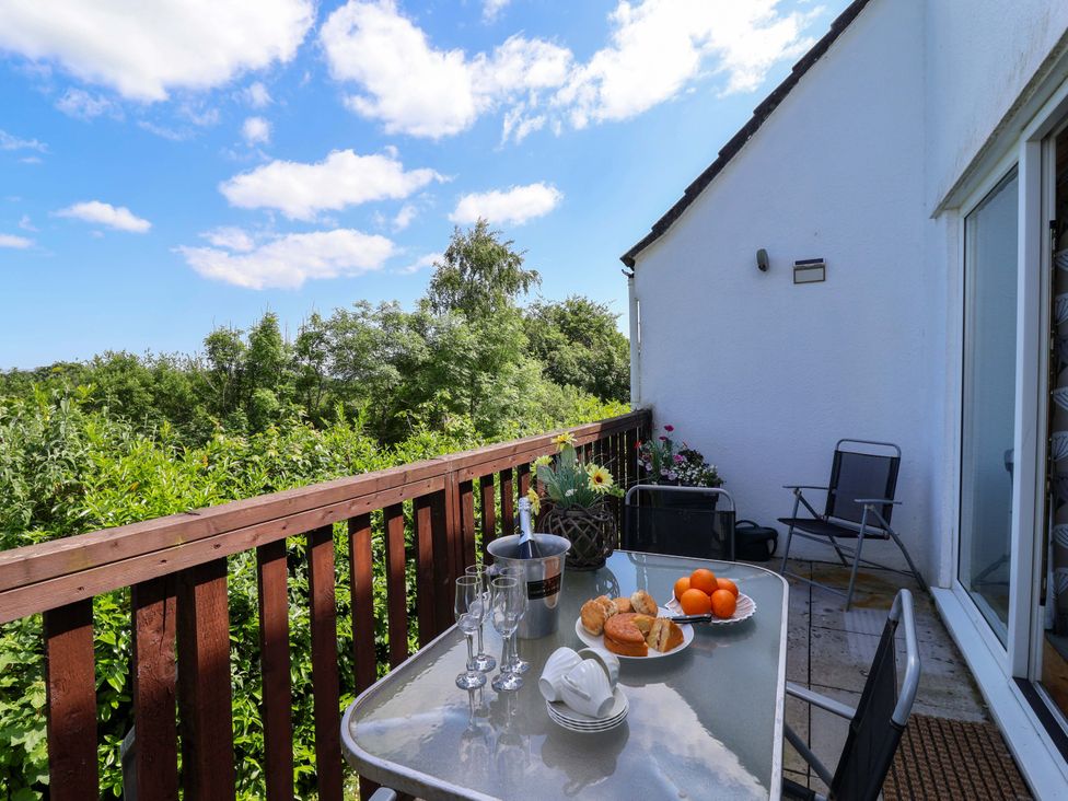 A balcony with a glass table and chairs overlooking greenery at 37 Tamar St Ann's Chapel near Callington