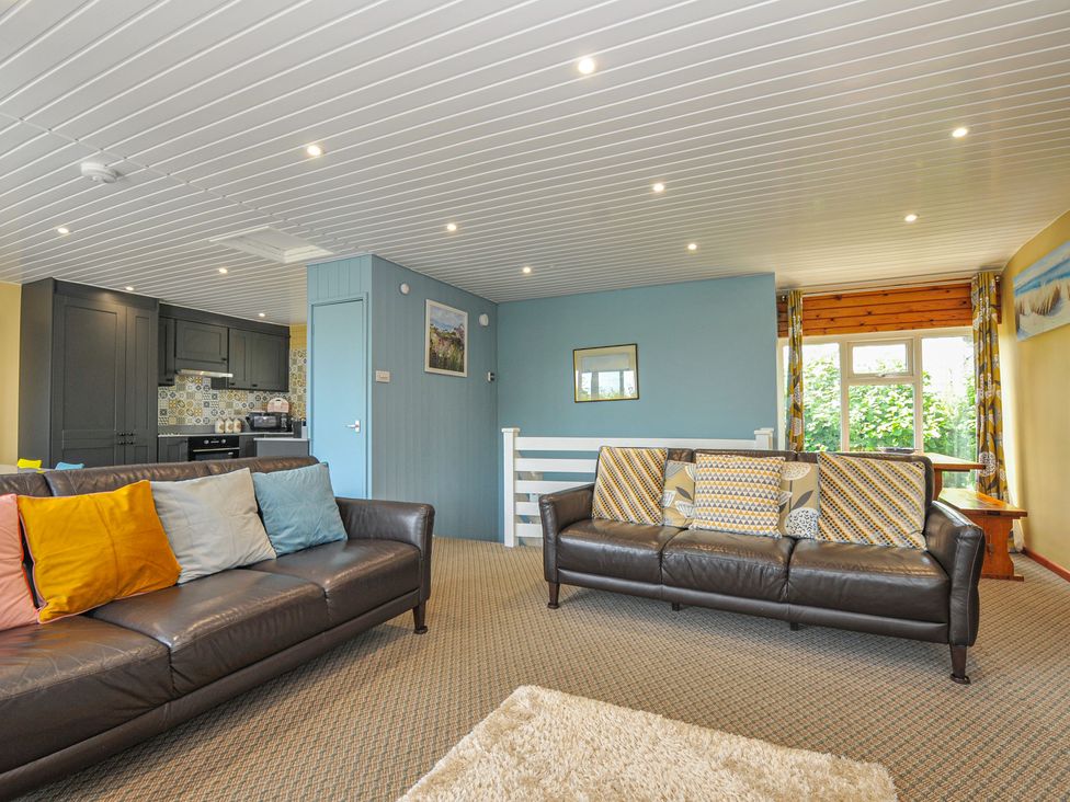 A living room with sofas and kitchen area at 37 Tamar St Ann's Chapel near Callington