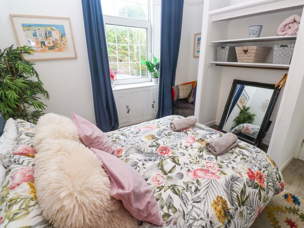 A bedroom with a bed, mirror, shelves and plants at Harbour View in St Ives