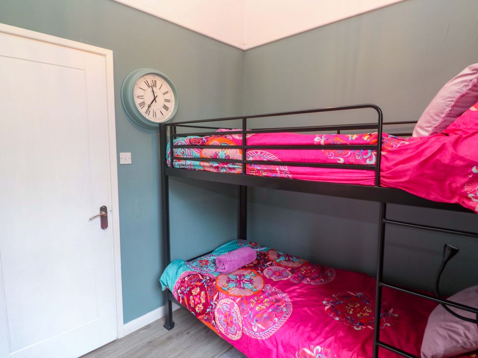 A bedroom with a bunk bed and wall clock at Harbour View in St Ives
