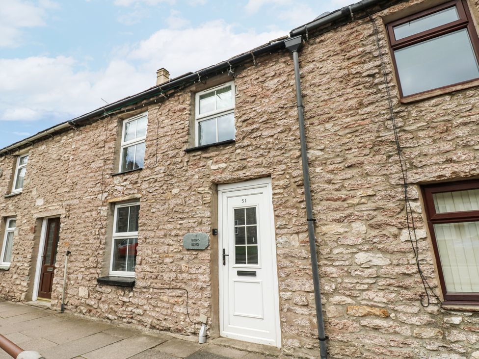 An exterior view of a stone cottage with front door and windows at Fettlers Cottage, 51 High Street Kirkby Stephen