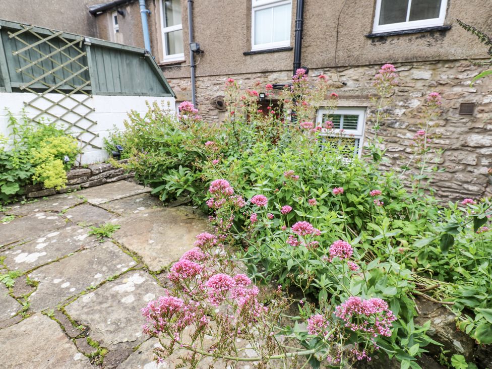 A garden with flowers and a stone path at Fettlers Cottage, 51 High Street, Kirkby Stephen