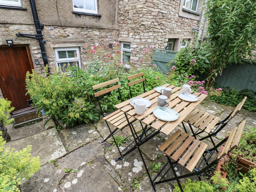 A garden setting with a dining table and chairs at Fettlers Cottage, 51 High Street Kirkby Stephen
