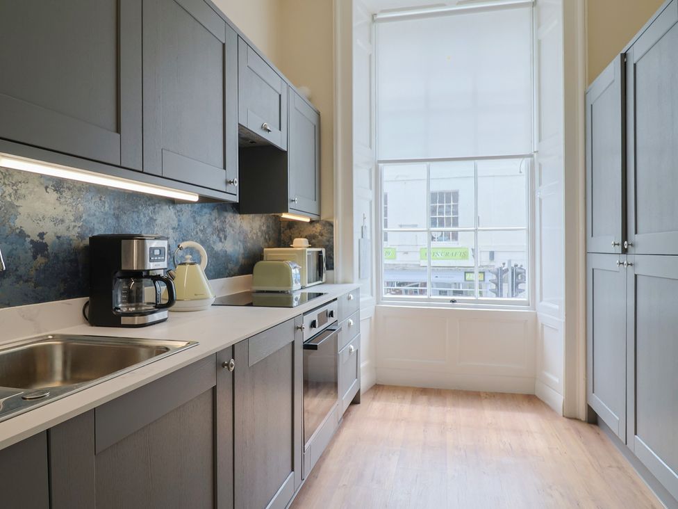 A kitchen with cabinets, sink, coffee maker, and kettle at FLAT 1 53a Broad Street (1 Bedroom Sleeping 2), Lyme Regis