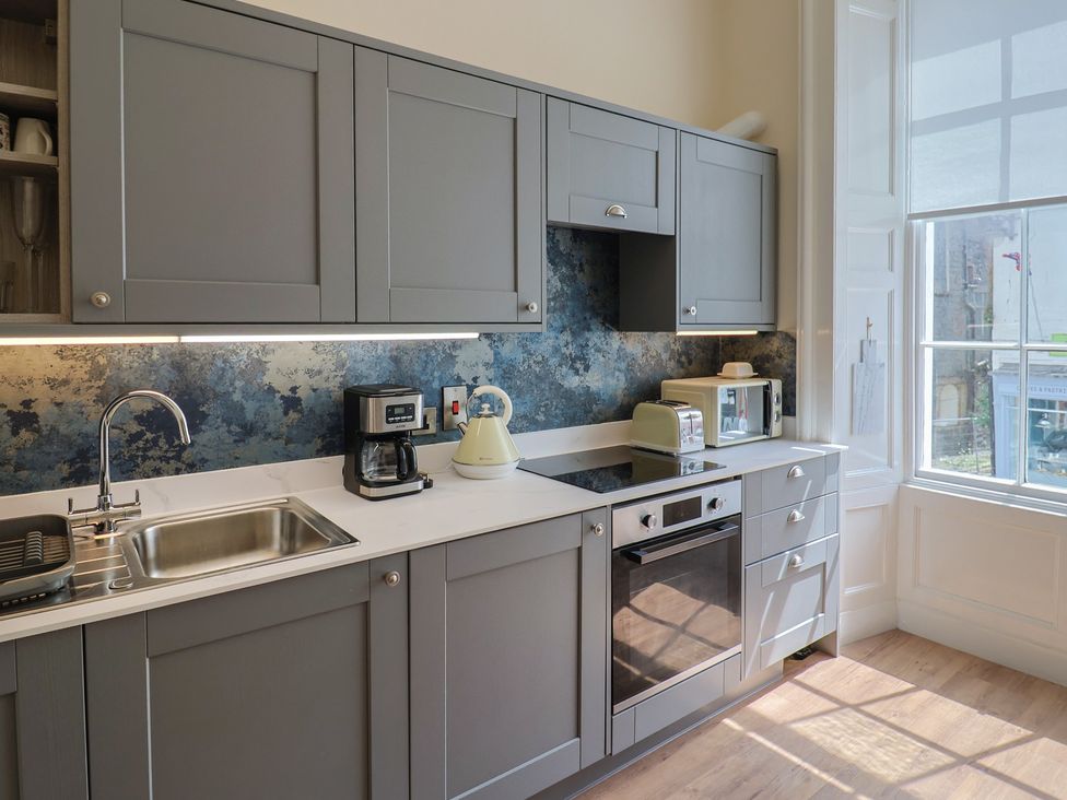A kitchen with cabinets, sink, coffee maker, and oven at FLAT 1 53a Broad Street (1 Bedroom Sleeping 2) Lyme Regis