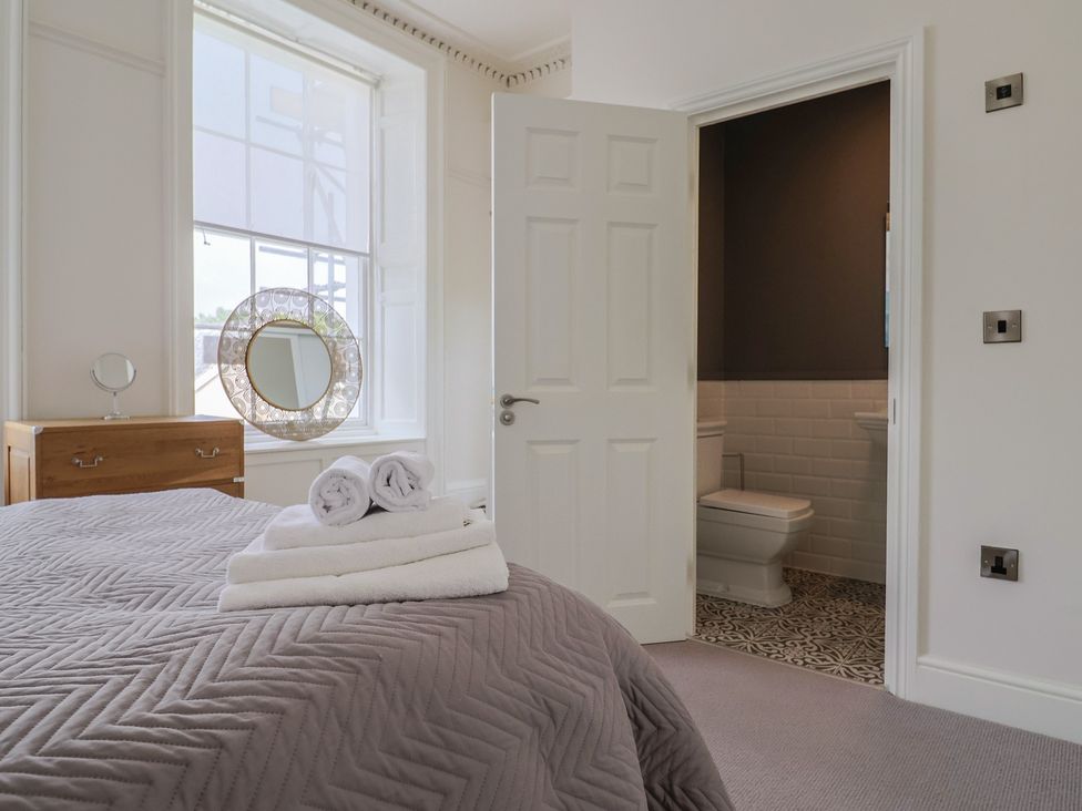 A bedroom with a bed and a door leading to a bathroom at FLAT 1 53a Broad Street (1 Bedroom Sleeping 2) Lyme Regis
