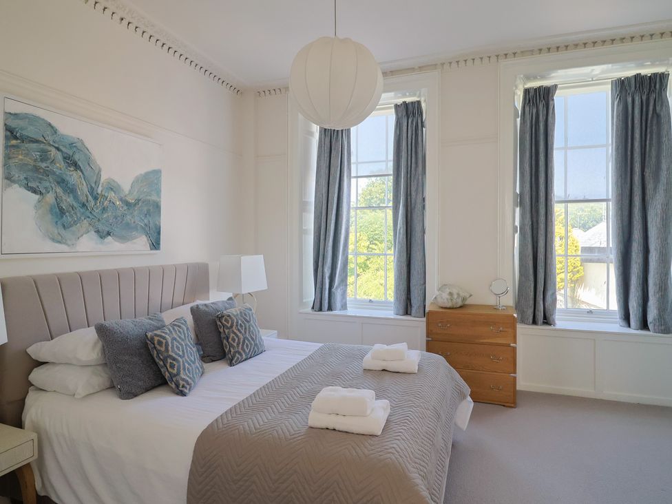 A bedroom with a bed and windows at The Tides in Lyme Regis