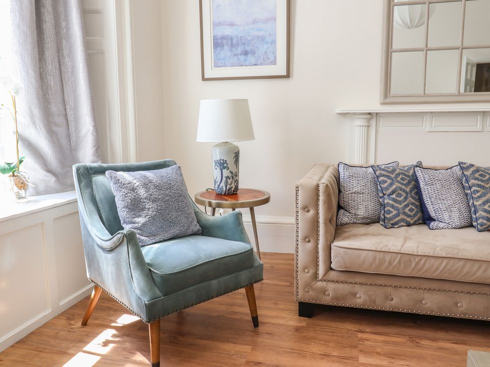 A living room with a blue armchair and beige sofa at The Tides Lyme Regis