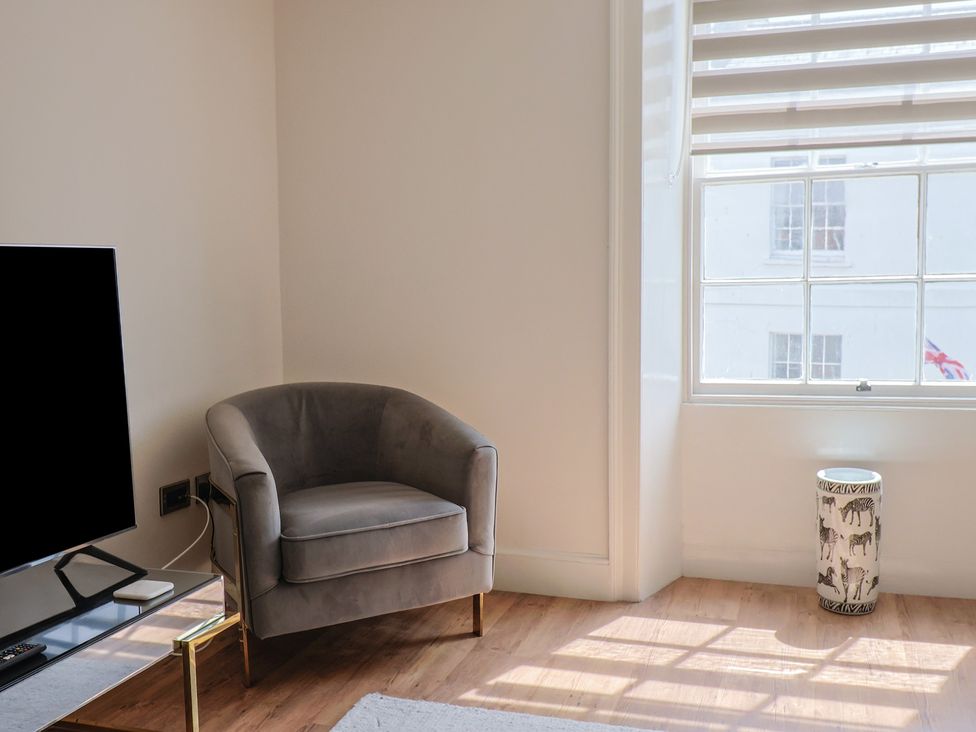 A living room with a television and an armchair at FLAT 2 53a Broad Street (1 Bedroom Sleeping2) Lyme Regis
