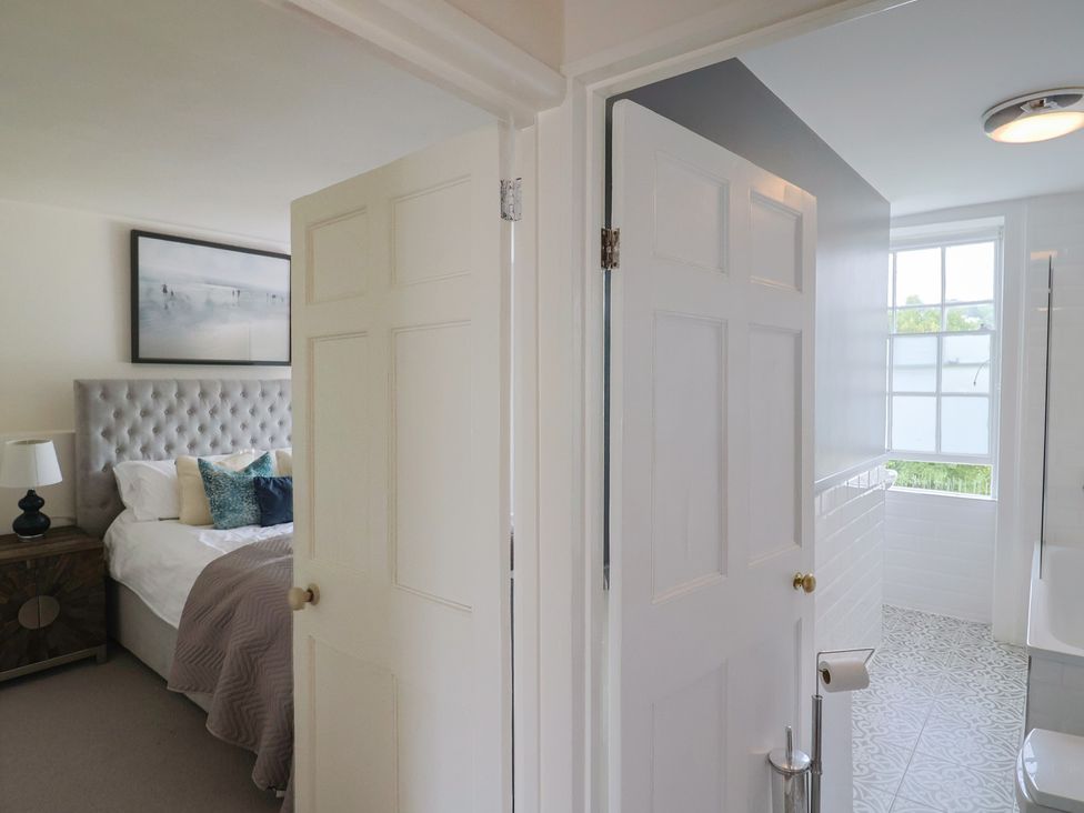 A bedroom with a bed and nightstand leading to a bathroom at FLAT 2 53a Broad Street (1 Bedroom Sleeping2) Lyme Regis