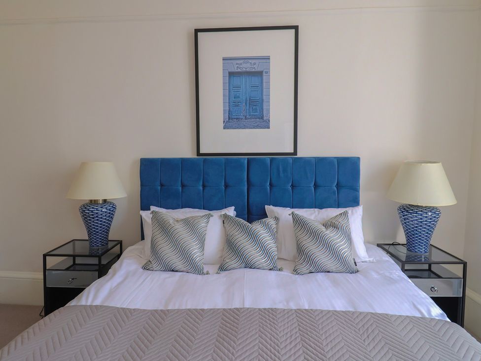 A bedroom with a blue bed and bedside tables at Saltwind in Lyme Regis