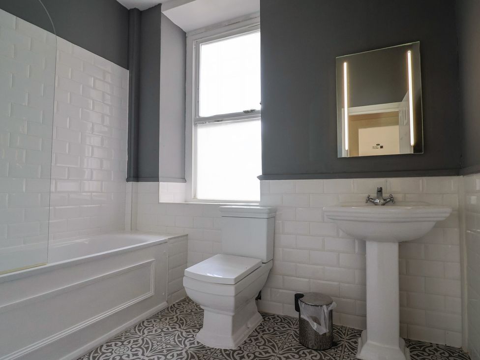 A bathroom with a bathtub, toilet, and sink at Saltwind in Lyme Regis
