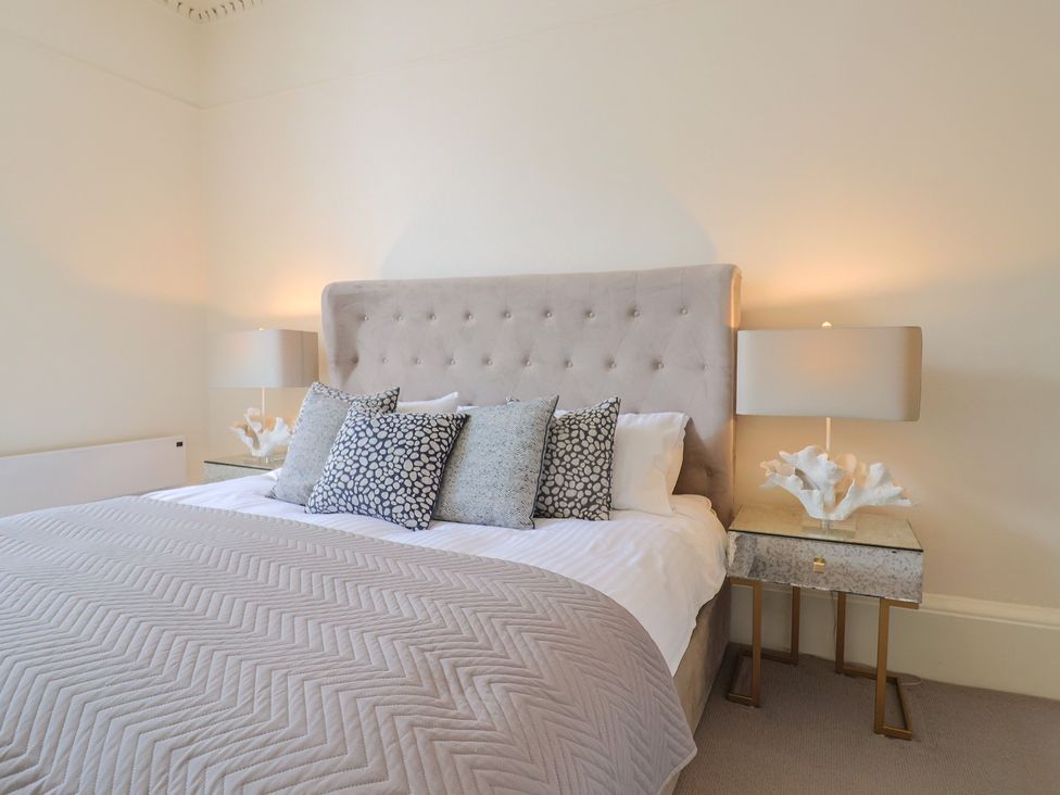 A bedroom with a bed, bedside lamp, and decorative objects at Saltwind in Lyme Regis
